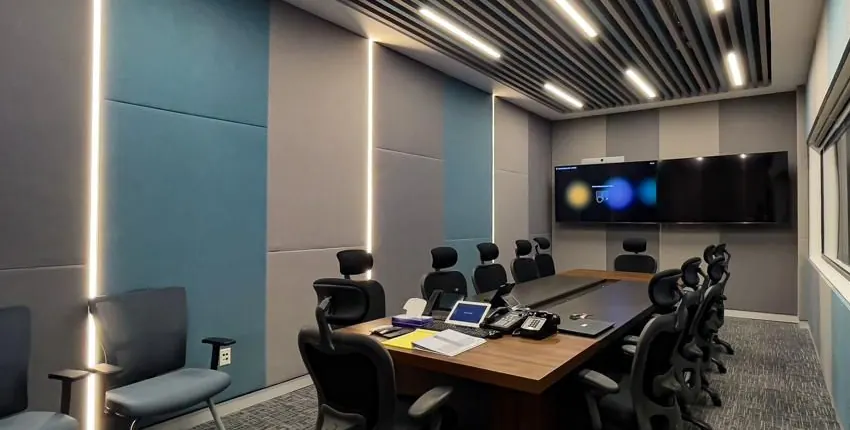 Meeting room lined with teal and grey fabric-wrapped acoustic wall panels and linear lighting