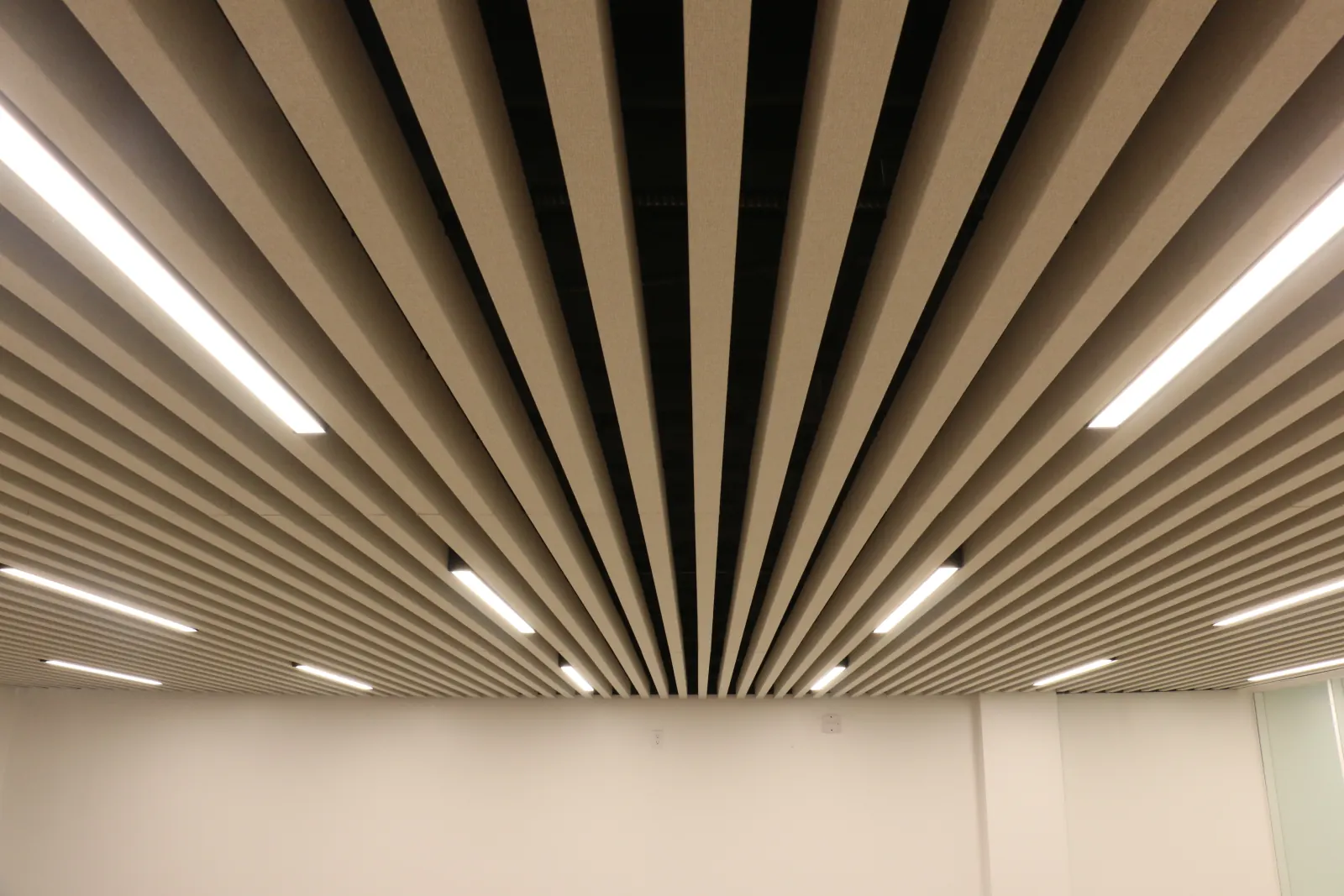 Acoustic baffles fanning out across an office ceiling, with linear lights between the blades